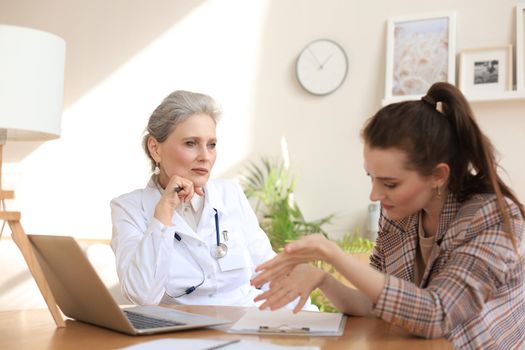 Middle aged female doctor therapist in consultation with patient in office