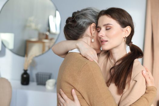 Portrait of old mother and mature daughter hugging at home. Happy trusted relations. Family concept