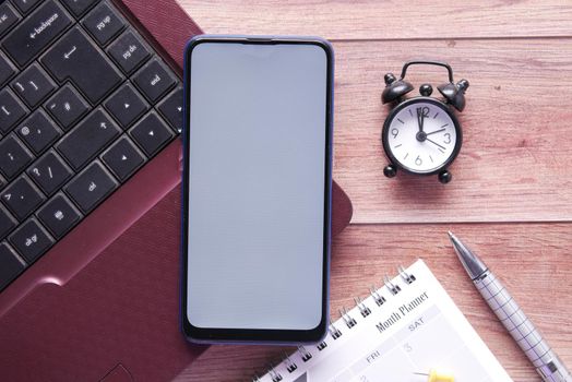 smart phone with empty screen, laptop on wooden background .