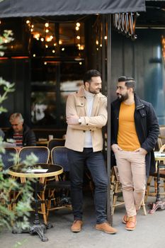 Two caucasian men standing and talking at street cafe. Concept of friendship and friends meeting.