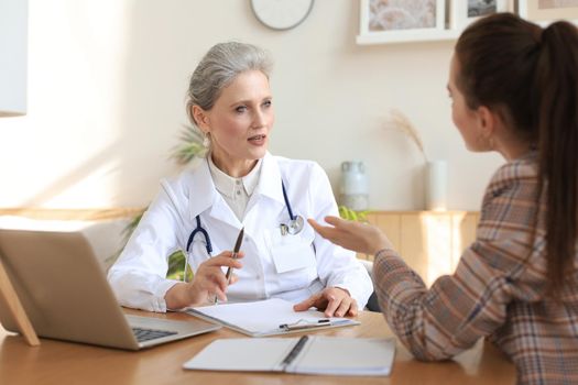 Middle aged female doctor therapist in consultation with patient in office