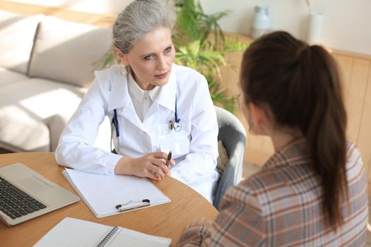 Middle aged female doctor therapist in consultation with patient in office
