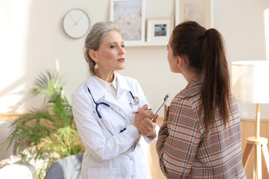 Friendly middle aged female doctor encouraging, supporting patient after medical examination
