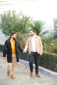European gays walking and holding hands in city. Concept of same sex couple and lgbt.