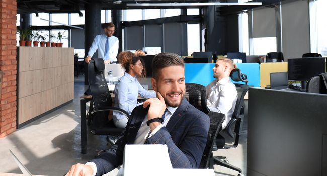 Businessman with colleagues in the background in modern office.