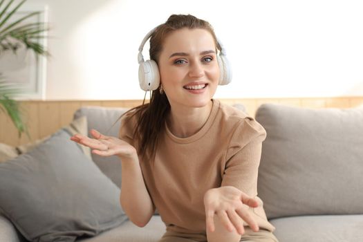 Smiling young woman blogger influencer working at home. Girl talking at web camera, making videochat or conference call, female recording vlog