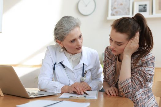 Middle aged female doctor therapist in consultation with patient in office