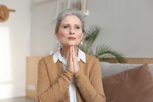 Middle aged woman praying, eyes opened, looking up, hoping for best, asking for forgiveness