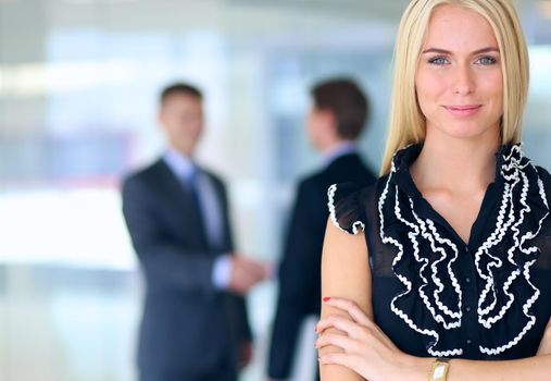 Business woman standing in foreground with a folder in her hands .