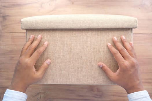 young man hand hold a box against yellow background ,