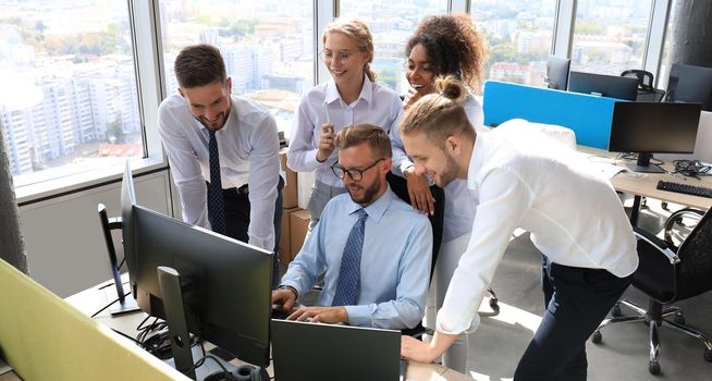 Group of young modern people in formalwear using modern technologies while working in the creative office.