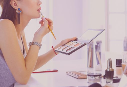 Brunette woman applying make up for a evening date in front of a mirror.