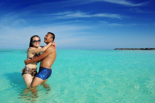 happy young asian couple enjoying summer and have on beautiful white sand beach