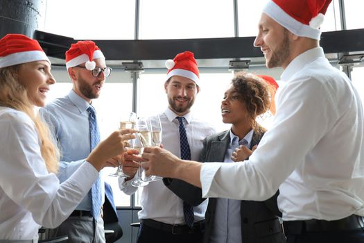 Office business coworkers celebrating winter holidays together at work and drinking champagne in office. Merry Christmas and Happy New Year