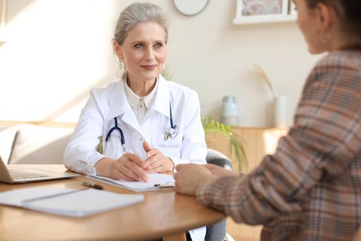 Middle aged female doctor therapist in consultation with patient in office
