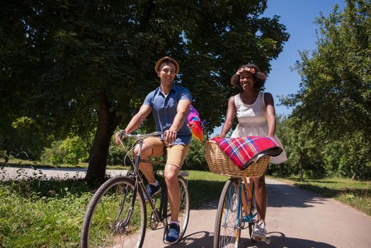 a young man and a beautiful African American girl enjoying a bike ride in nature on a sunny summer day