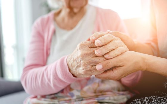 Senior woman and her daughter holding hands. Grandmother with granddaughter family moments together
