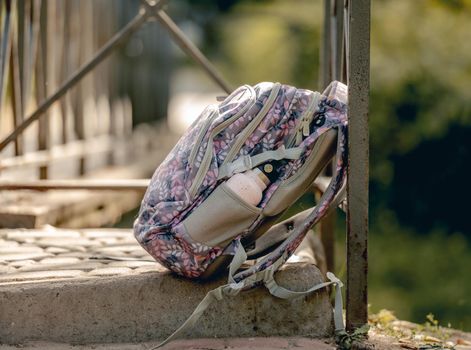 School backpack lying at the street. Casual schoolbag for primary class girl kid pupil