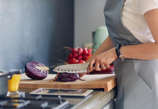 Woman cooking in new kitchen making healthy food with vegetables.