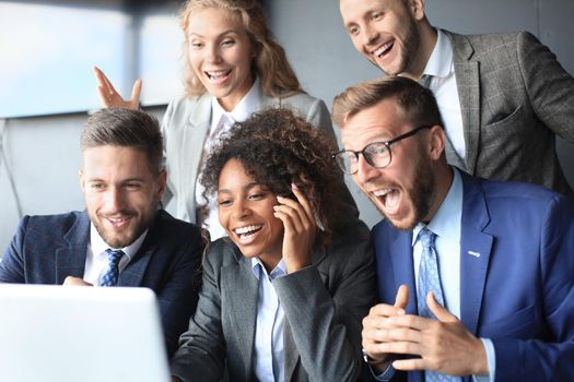 Happy business people laugh near laptop in the office. Successful team coworkers joke and have fun together at work