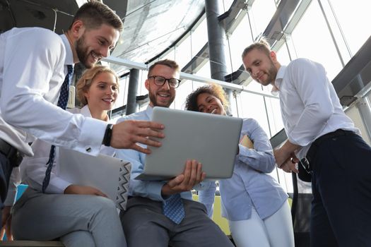 Group of modern business people using laptop and smiling while standing in the office