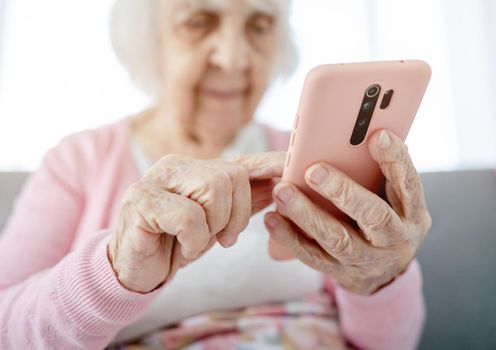 Senior woman hands with smartphone closeup. Elderly female person with modern cell phone