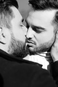 Black and white portrait of handsome hugging and kissing gays. Concept of love, same sex couple and lgbt.
