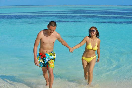 happy young asian couple enjoying summer and have on beautiful white sand beach