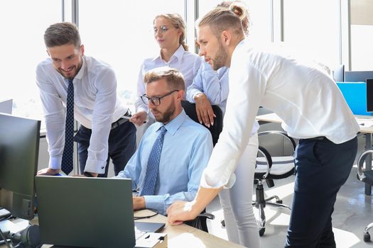 Group of young modern people in formalwear using modern technologies while working in the creative office.