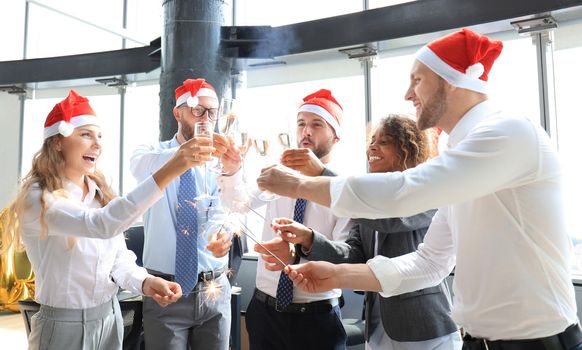 Young business partners are lighting bengal lights and drinking champagne in a modern office. Merry Christmas and Happy New Year