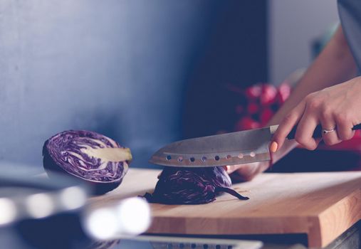 Woman cooking in new kitchen making healthy food with vegetables.