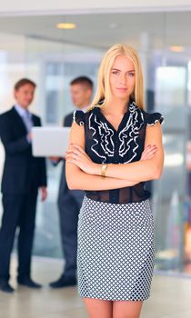 Business woman standing in foreground in office .