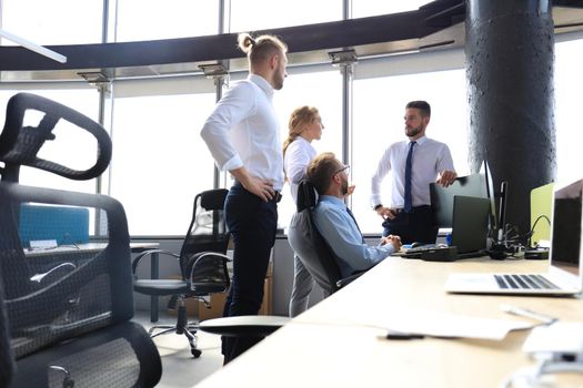 Group of young business people discussing something while working in the creative office.