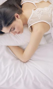 Pretty woman lying down on her bed at home.