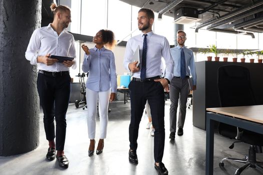 Modern business people discussing business and smiling while walking through the office corridor.