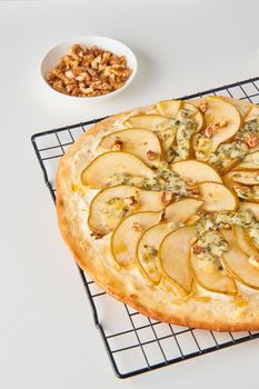 Part of fruit homemade sweet pear pizza with cheese and honey, Rustic Italian savory food with pastry dough, vertical