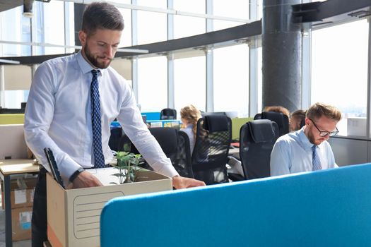 Sad dismissed worker are taking his office supplies with him from office.