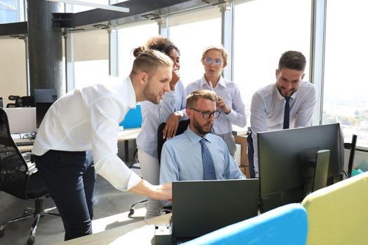 Group of young modern people in formalwear using modern technologies while working in the creative office.