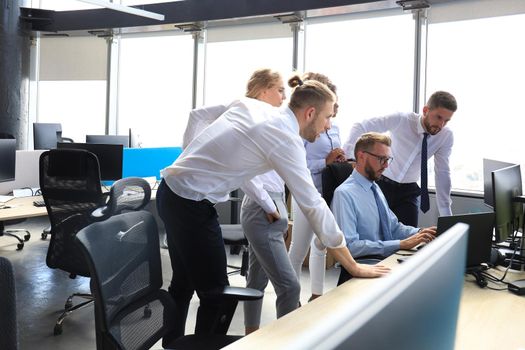 Group of young modern people in formalwear using modern technologies while working in the creative office.