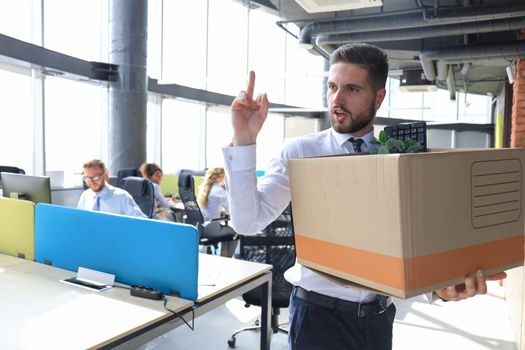 Dismissed worker going from the office with his office supplies showing fuck.