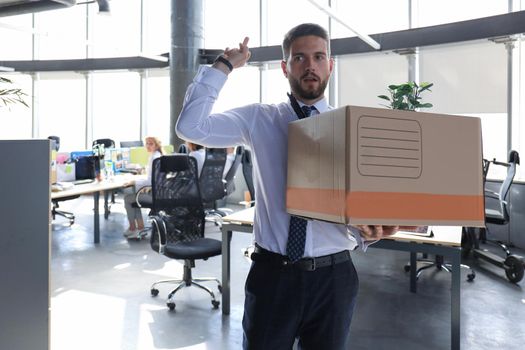 Dismissed worker going from the office with his office supplies showing fuck.