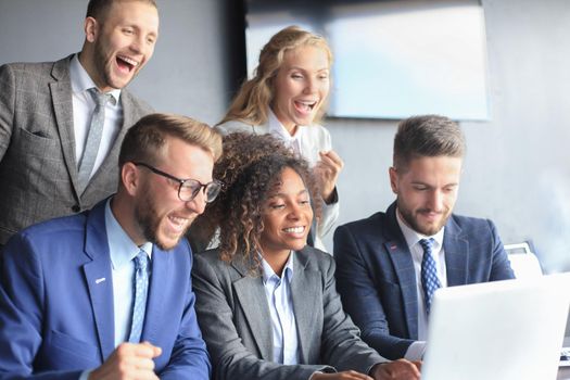 Happy business people laugh near laptop in the office. Successful team coworkers joke and have fun together at work