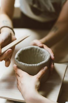 Woman making ceramic pottery, four hands close-up, focus on potters, palms with pottery, concept for workshop and master class, selective focus