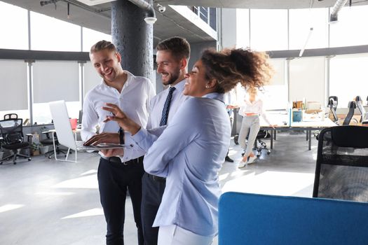 Group of modern business people are talking and smiling while standing in the office hallway.