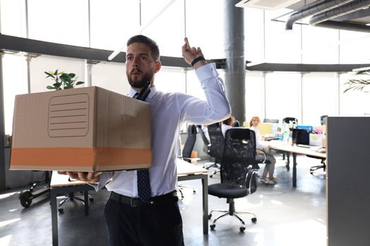 Dismissed worker going from the office with his office supplies showing fuck.