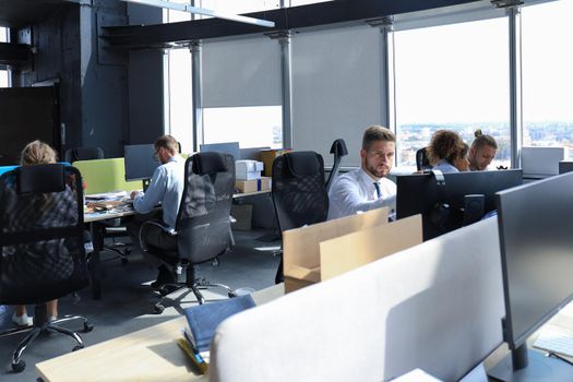 Group of young modern people in formalwear using modern technologies while working in the creative office.