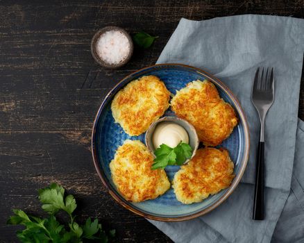 Hashbrown, hash brown potatoes fried pancakes, traditional american cuisine. Crispy hashed browned potatoes in blue plate on dark brown table, top view.