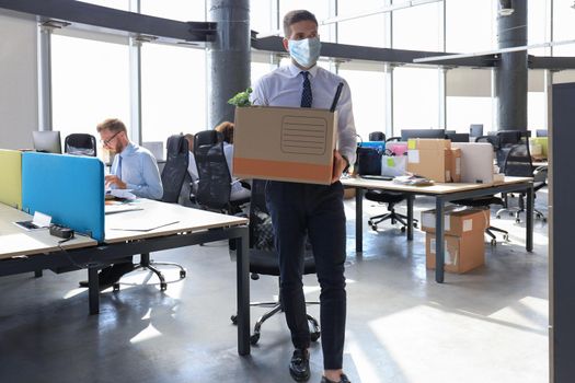 Dismissal employee in preventive medical mask in an epidemic coronavirus. Sad dismissed worker are taking his office supplies with him from office