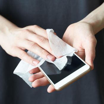 Woman wash cell phone with wet wipes, to prevent illness Novel coronavirus 2019-nCoV after public place. Antiseptic, Hygiene and Healthcare concept