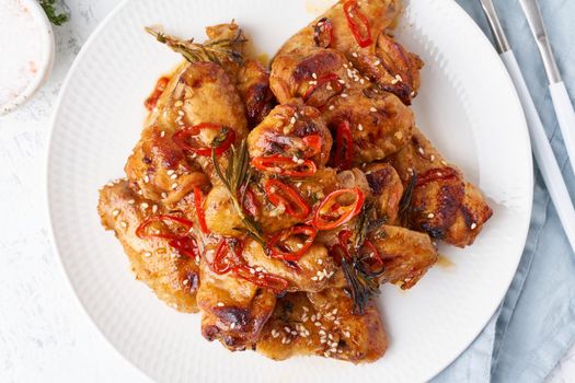 Barbecue chicken wings. Slow cooker sweet and spicy. Oven baked marinated chiken on plate in bbq red sauce. Hot korean food. Top view, close up